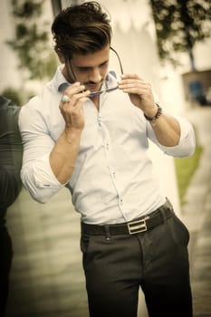 One handsome elegant young man in urban setting in European city, standing