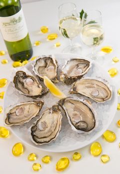 Oysters on ice and with a piece of lemon and wine bottle and glass