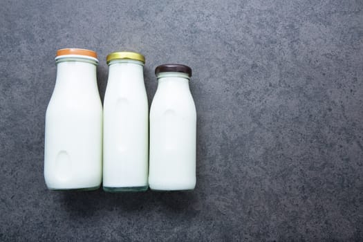 Milk bottle on dark stone background. Top view with copy space.