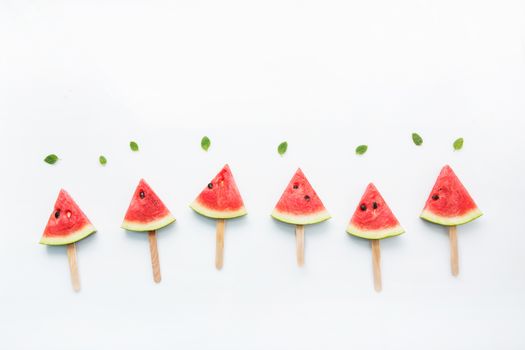 Watermelon slice popsicles and paper mint on white wooden background.