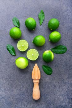 Fresh limes and wooden juicer on white background. Top view with copy space