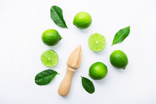 Fresh limes and wooden juicer on white background. Top view with copy space