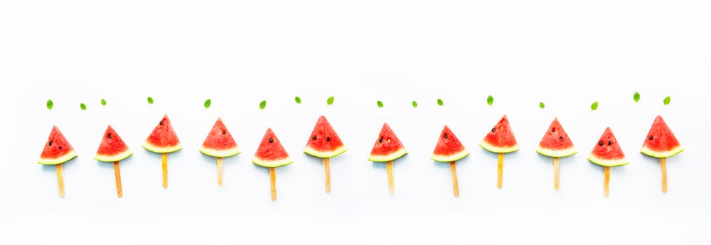 Watermelon slice popsicles and paper mint on white wooden background.