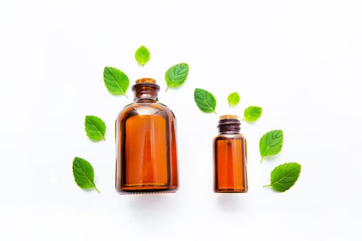 Natural Mint Essential Oil in a Glass Bottle with Fresh Mint Leaves on white over wooden background.