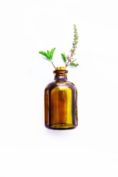 Holy Basil  Essential Oil in a Glass Bottle with Fresh Holy Basil white wooden  background.     