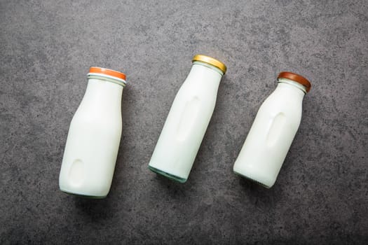 Milk bottle on dark stone background. Top view with copy space.