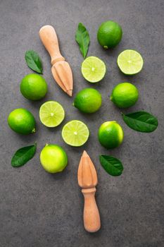 Fresh limes and wooden juicer on dark stone background. Top view