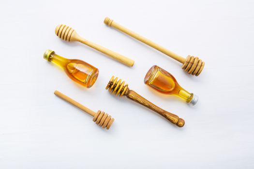 Honey wooden dipper and little honey bottle on white wooden background.