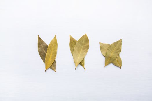 Dried bay leaves on white wooden background.