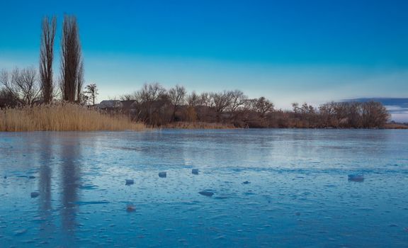 Winter paysage landscape of frozen village on iced lake river under snow