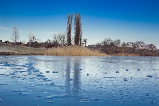 Winter paysage landscape of frozen village on iced lake river under snow