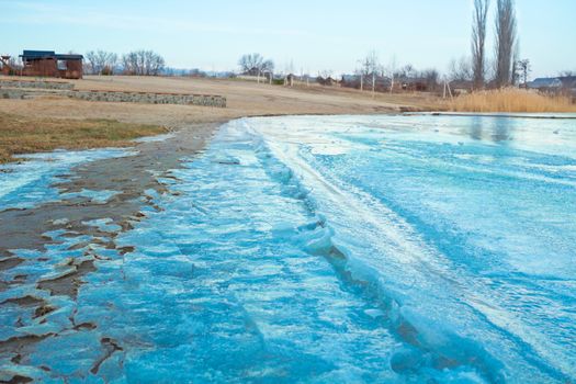 Blue iced frozen lake river on winter cold sandy beach