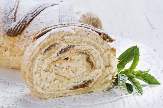 Biscuit roll with condensed milk on a table, selective focus