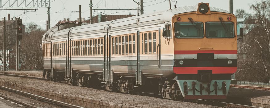 Old yellow passenger diesel train moving at the terminal