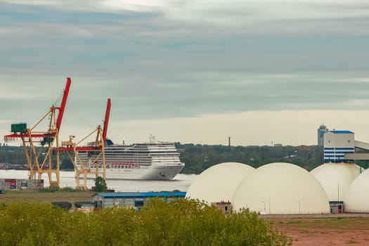 Big white cruise liner sailing past the cargo port