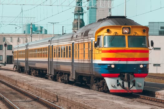 Old yellow passenger diesel train moving at the terminal