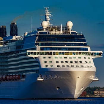 Giant white passenger ship moving past the port on a clear day