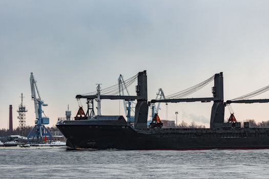 Black bulk carrier sailing to the sea in cold winter