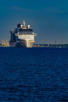 Giant white passenger ship moving past the port on a clear day