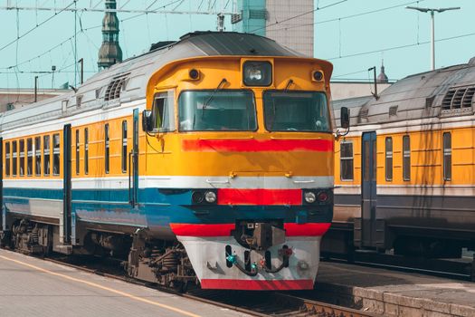 Old yellow passenger diesel train moving at the terminal