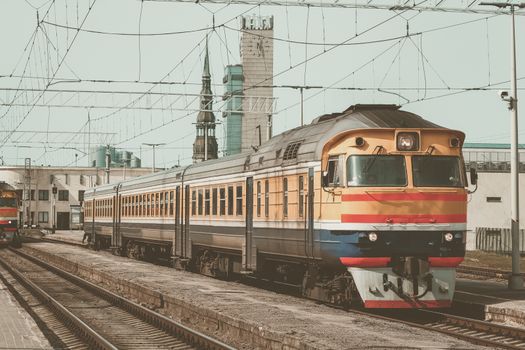 Old yellow passenger diesel train moving at the terminal