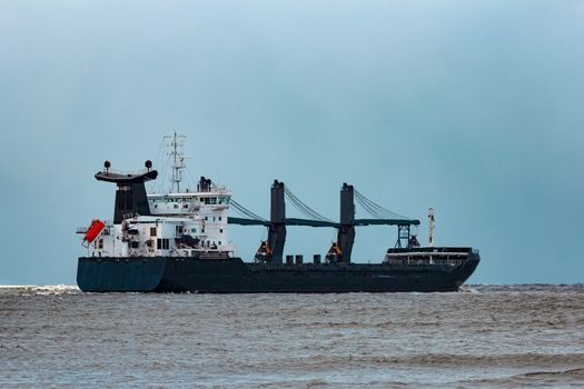 Black bulk carrier sailing to the sea in cold winter