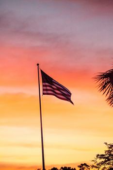 Red, white and blue American flag blows in the wind  at sunrise