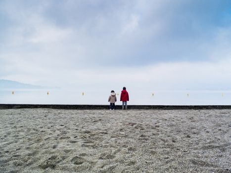 Children playing on the beach in winter, Lake Maggiore, Ispra, Lombardy, Italy