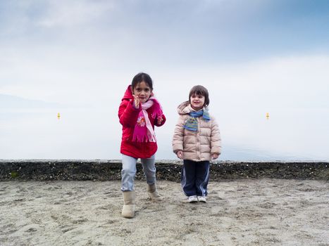 Children playing on the beach in winter, Lake Maggiore, Ispra, Lombardy, Italy