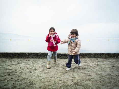 Children playing on the beach in winter, Lake Maggiore, Ispra, Lombardy, Italy