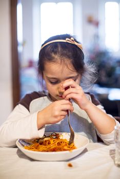 child eats spaghetti at home in the kitchen