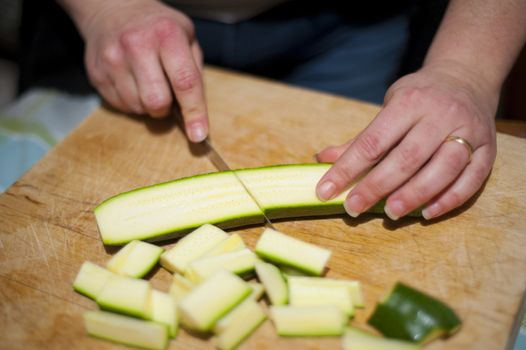 woman's hands with zucchini-cut ring on the kitchen cutting board to prepare dinner or lunch