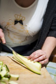 woman's hands with zucchini-cut ring on the kitchen cutting board to prepare dinner or lunch