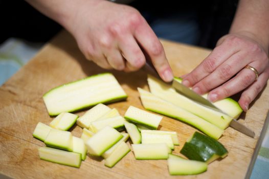 woman's hands with zucchini-cut ring on the kitchen cutting board to prepare dinner or lunch