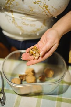 woman's hands open up pecan nuts in a bowl