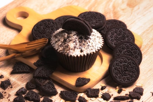 Chocolate cupcake and cookies are on wooden plate