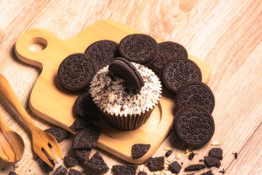 Chocolate cupcake and cookies are on wooden plate