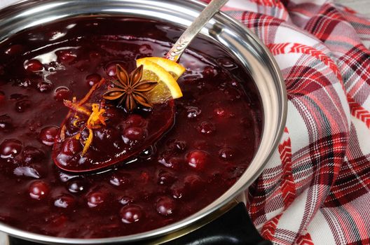 Freshly cooked cranberry sauce with orange peel and citrus slices in a saucepan