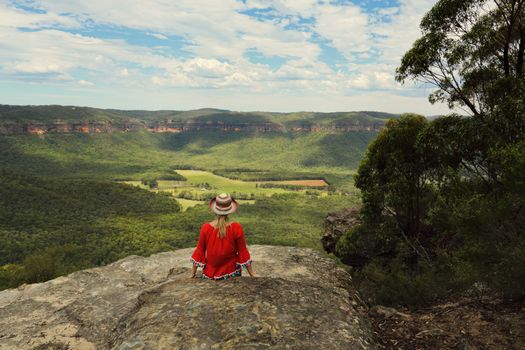 Woman relaxing with a beautiful vista of blue mountains cliffs and valley views