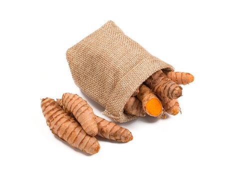 Raw turmeric root in burlap sack isolated on white background