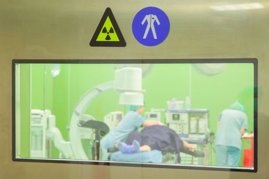 A sign for radiation and work clothes on a door of a surgery room while patient being prepared for operation.