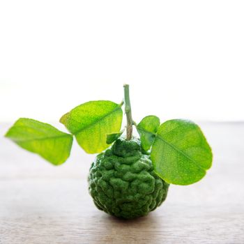 Pesticide free organic kaffir lime with leaves on wooden background.