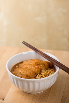 Hot and spicy Malaysian curry noodle with chopsticks on table.