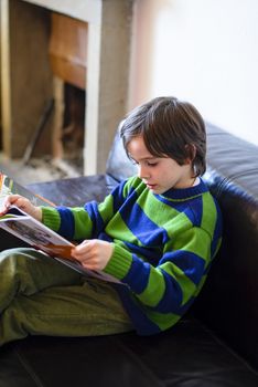 child reads a book sitting on the couch