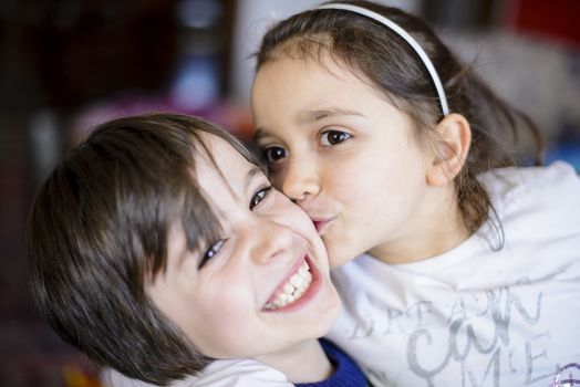 children brothers kiss on the cheek laughing and playing at home