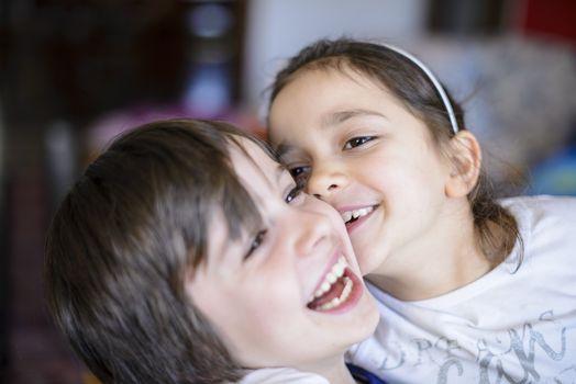 children brothers kiss on the cheek laughing and playing at home