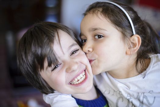 children brothers kiss on the cheek laughing and playing at home