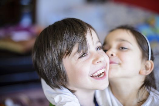 children brothers kiss on the cheek laughing and playing at home