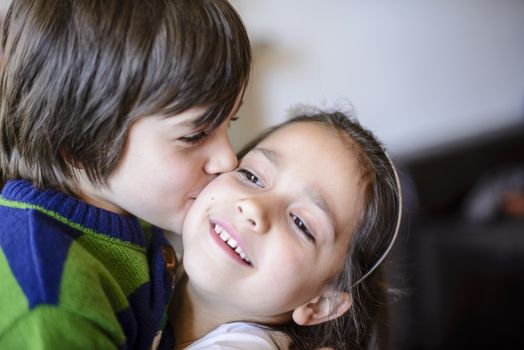 children brothers kiss on the cheek laughing and playing at home