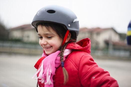 little girl learns to skate with rollerblading at the basketball court on a winter day